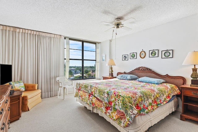 bedroom with ceiling fan, light carpet, and a textured ceiling