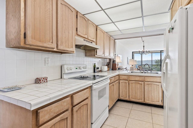 kitchen with white appliances, sink, light tile patterned floors, pendant lighting, and an inviting chandelier