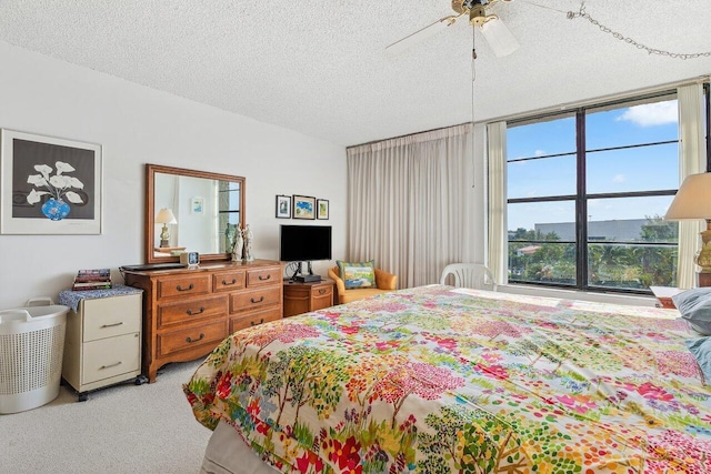 bedroom with ceiling fan, carpet floors, and a textured ceiling