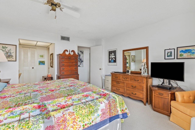 carpeted bedroom with ceiling fan, a closet, and a textured ceiling