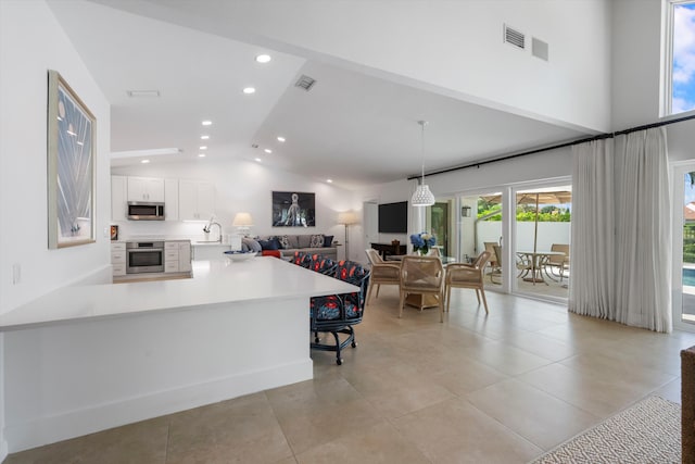 kitchen with white cabinetry, kitchen peninsula, decorative light fixtures, lofted ceiling, and appliances with stainless steel finishes