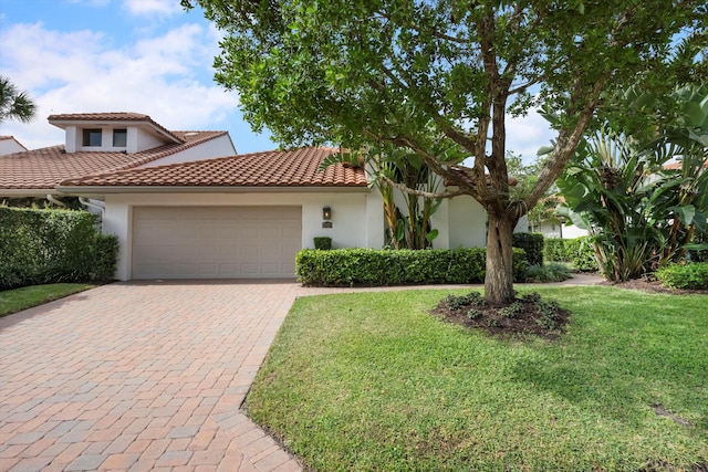 mediterranean / spanish-style house featuring a front yard and a garage