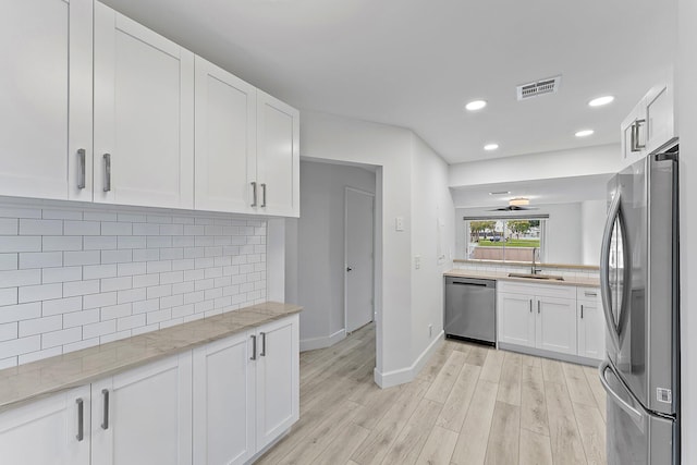 kitchen featuring light stone countertops, stainless steel appliances, sink, light hardwood / wood-style flooring, and white cabinets