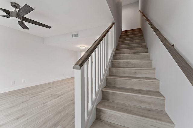 staircase with ceiling fan and wood-type flooring