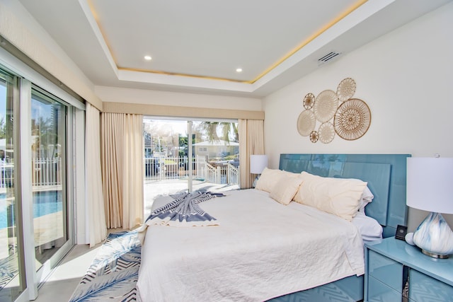 bedroom with multiple windows, access to outside, and a tray ceiling