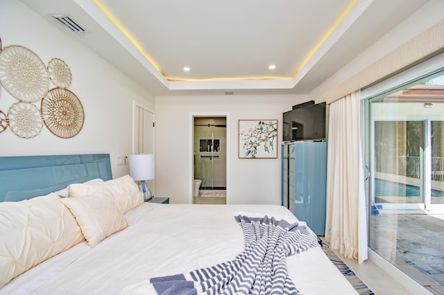 bedroom featuring access to exterior, a raised ceiling, and ensuite bath