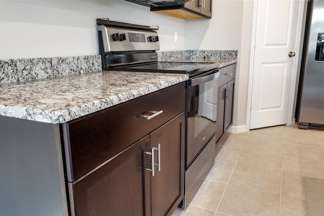 kitchen featuring stainless steel appliances, light stone countertops, light tile patterned floors, and dark brown cabinetry