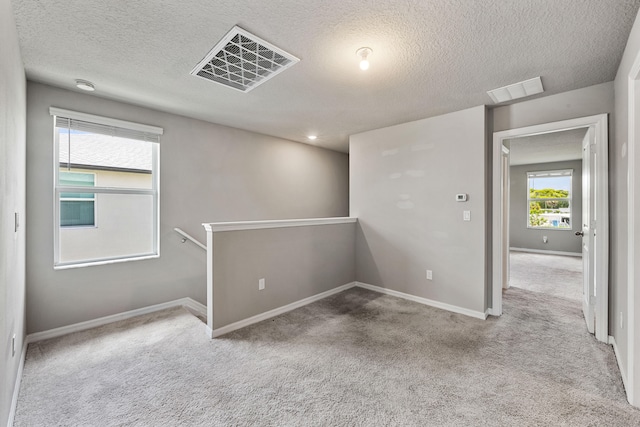 empty room featuring light colored carpet and a textured ceiling