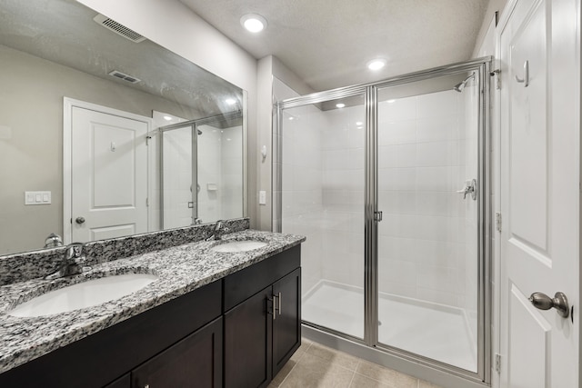 bathroom featuring walk in shower, vanity, a textured ceiling, and tile patterned flooring