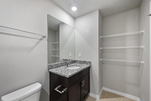 bathroom featuring tile patterned floors, vanity, toilet, and a textured ceiling