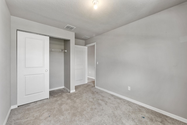 unfurnished bedroom with a textured ceiling, light carpet, and a closet