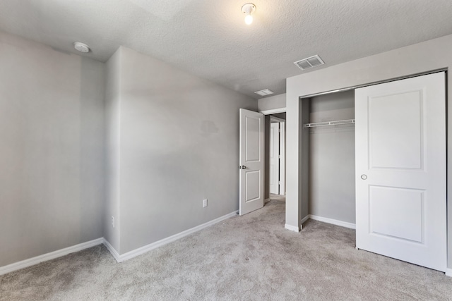 unfurnished bedroom featuring light colored carpet, a textured ceiling, and a closet