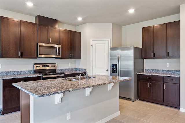 kitchen with sink, a breakfast bar, appliances with stainless steel finishes, an island with sink, and dark brown cabinets