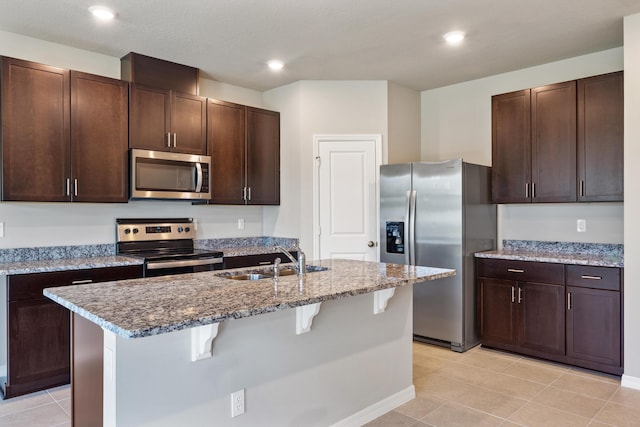 3526 Joshua Tree St, Palm Springs, FL 33461 - kitchen with stainless steel appliances, a sink, a kitchen bar, light stone countertops, and dark brown cabinetry