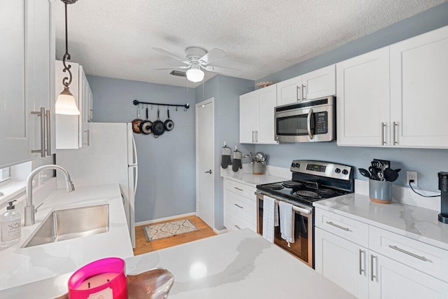 kitchen with sink, ceiling fan, white cabinetry, appliances with stainless steel finishes, and decorative light fixtures