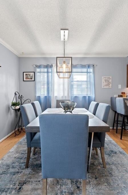 27 Lake Vista Trl Unit 107, Port Saint Lucie, FL 34952 - dining area featuring healthy amount of natural light, crown molding, a textured ceiling, wood finished floors, and a chandelier