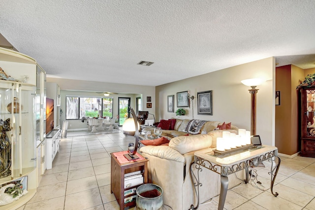 living area with light tile patterned floors, a textured ceiling, visible vents, and baseboards