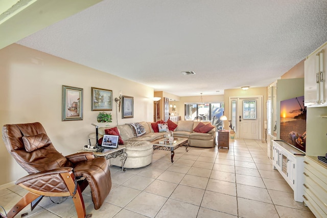 living area featuring light tile patterned floors, a textured ceiling, and visible vents