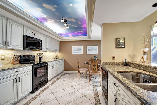kitchen featuring tasteful backsplash, a raised ceiling, white cabinets, black appliances, and baseboards