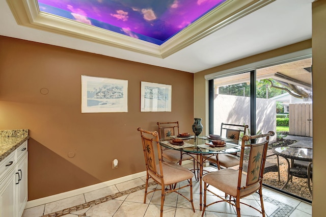 dining space with light tile patterned floors, baseboards, a raised ceiling, and crown molding