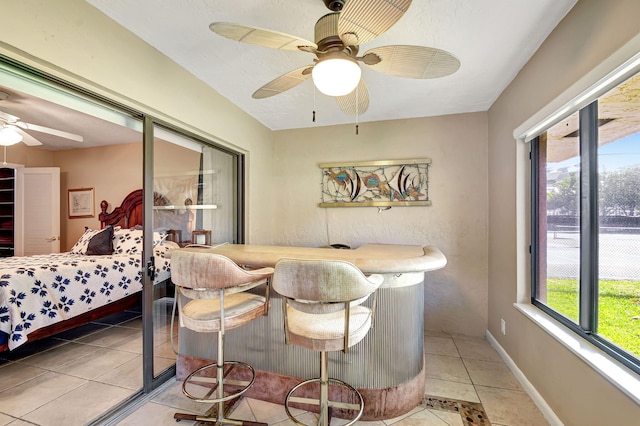 interior space with ceiling fan, a dry bar, light tile patterned flooring, and baseboards