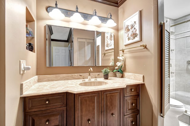 bathroom featuring tiled shower, crown molding, vanity, and toilet