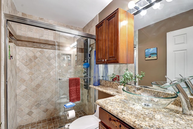 bathroom featuring toilet, a shower stall, and vanity