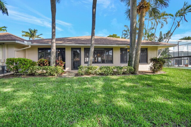 ranch-style house featuring a front lawn and stucco siding