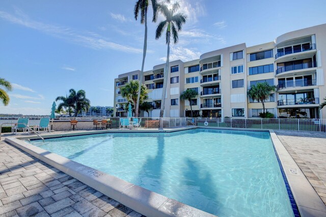 view of swimming pool featuring a patio area, a water view, and an in ground hot tub