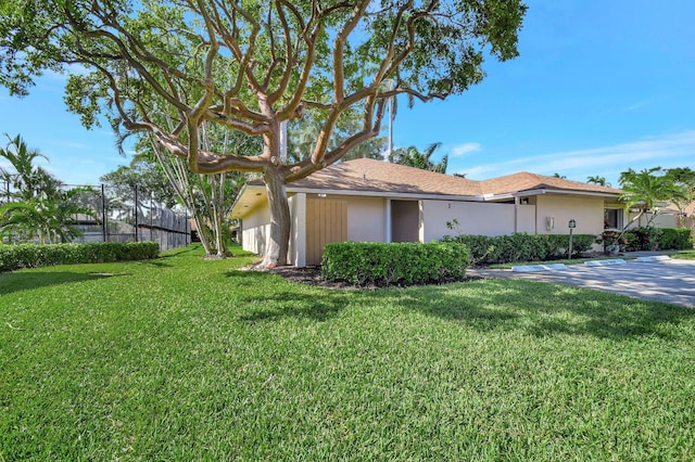 view of side of property featuring fence, a lawn, and stucco siding