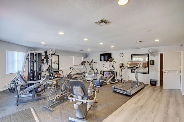 workout area with recessed lighting, visible vents, a textured ceiling, and baseboards
