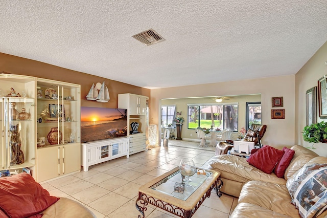 living room with ceiling fan, light tile patterned floors, and a textured ceiling