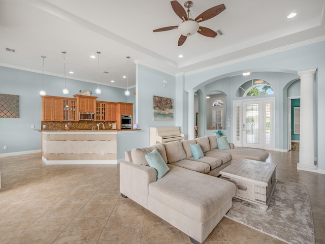 living room with sink, light tile patterned floors, ornate columns, and crown molding