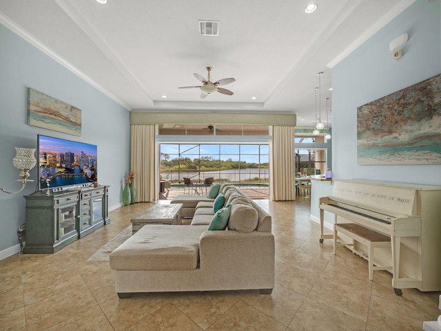 living room featuring light tile patterned flooring, crown molding, ceiling fan, and a raised ceiling