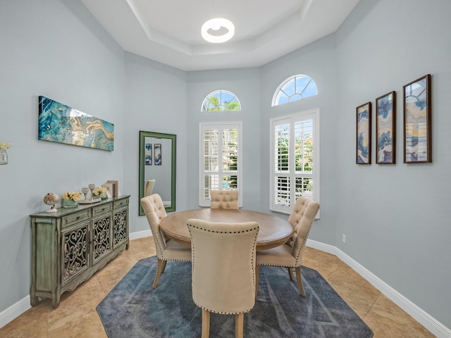 tiled dining area featuring a high ceiling and a tray ceiling