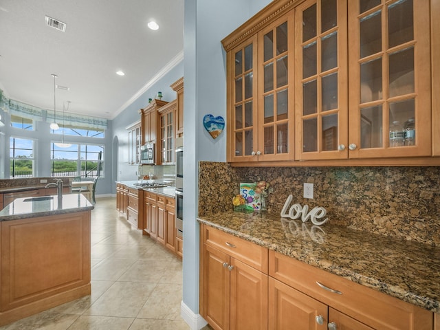 kitchen with stainless steel appliances, decorative light fixtures, dark stone counters, and crown molding