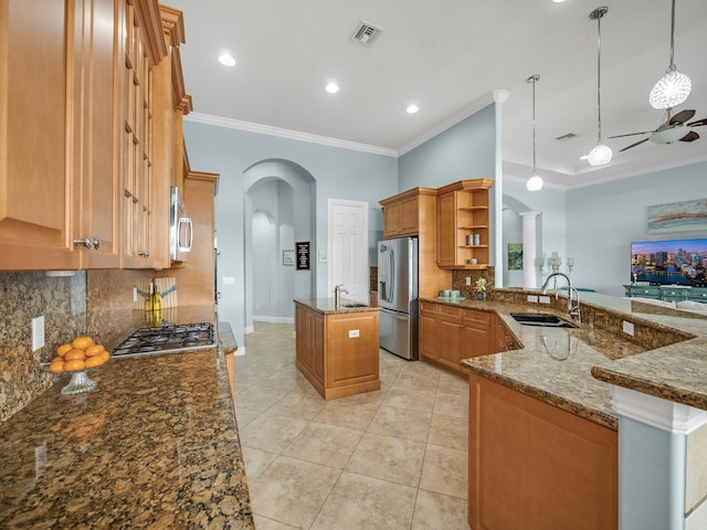 kitchen featuring stainless steel appliances, kitchen peninsula, hanging light fixtures, sink, and dark stone countertops