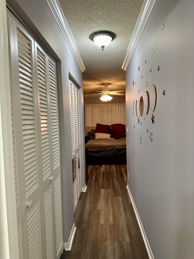 hall featuring dark hardwood / wood-style floors, a textured ceiling, and ornamental molding