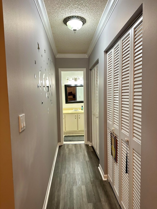 corridor featuring dark wood-type flooring, sink, a textured ceiling, and crown molding