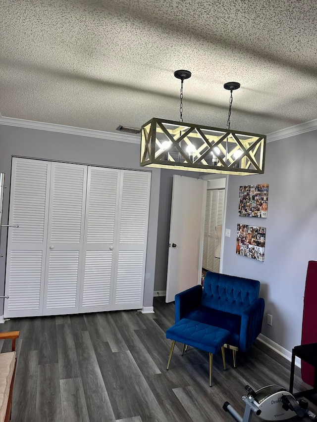 living area featuring ornamental molding, dark wood-type flooring, and a textured ceiling