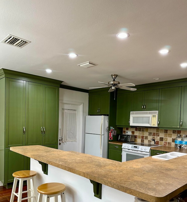 kitchen featuring white appliances, a kitchen bar, sink, and green cabinets