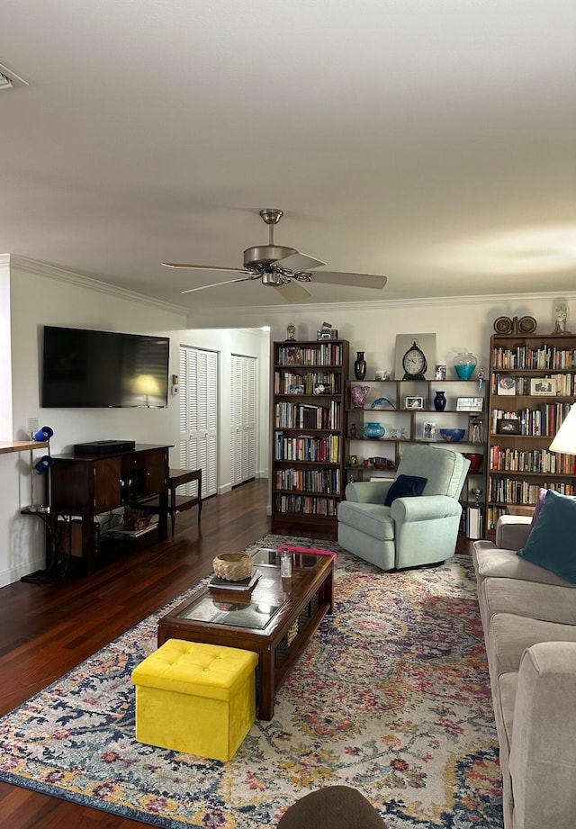 living room featuring dark wood-type flooring, ceiling fan, and crown molding