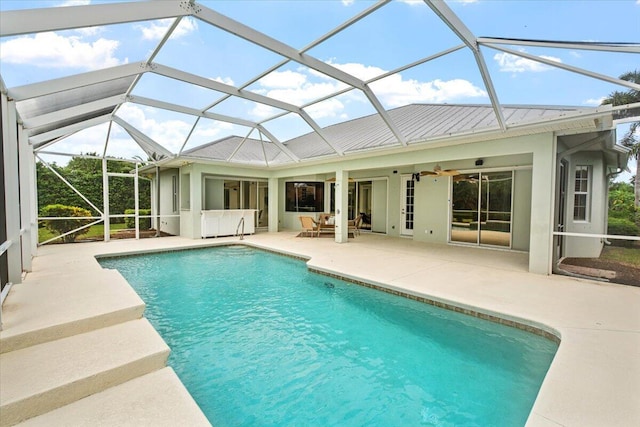 view of swimming pool with glass enclosure, ceiling fan, and a patio area