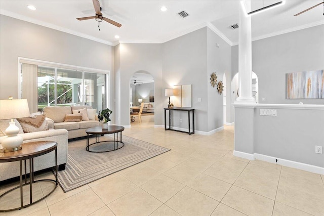 living room with ceiling fan, light tile patterned flooring, ornamental molding, and a high ceiling