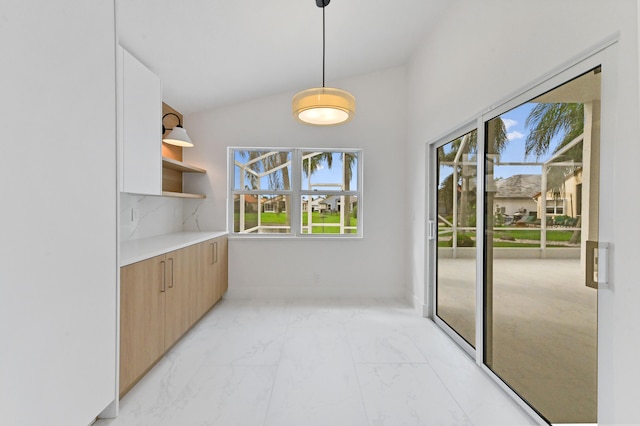 interior space with decorative light fixtures, vaulted ceiling, and backsplash