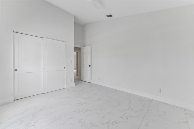 unfurnished bedroom featuring a towering ceiling, ceiling fan, and a closet