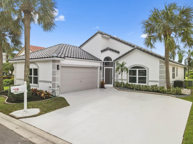 mediterranean / spanish house with a garage and central AC unit