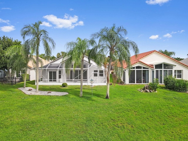 back of house with a lanai and a lawn