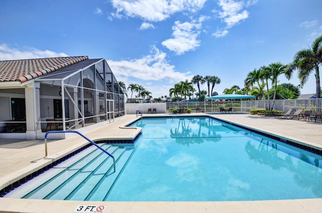 view of swimming pool featuring glass enclosure and a patio