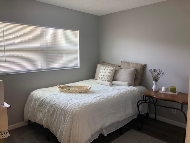 bedroom with dark hardwood / wood-style flooring and multiple windows